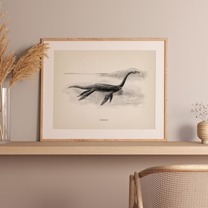 Pode incluir: Ilustra&ccedil;&atilde;o vintage emoldurada de um plesiosauro, um r&eacute;ptil marinho pr&eacute;-hist&oacute;rico, em tons s&eacute;pia. A obra de arte &eacute; apresentada sobre um fundo claro, com a palavra "Plesiosaur" abaixo. A moldura &eacute; de cor de madeira clara.