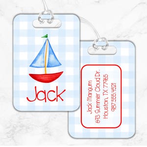 May include: Blue and white gingham luggage tag with a red and blue sailboat illustration. The tag has a clear plastic loop for attaching to luggage. The text "Jack" is printed in red on the tag. The back of the tag has a red border and the text "Jack mangum 693 Summer Cloud Dr. Houston, TX 77965 987.555.4521" is printed in red.