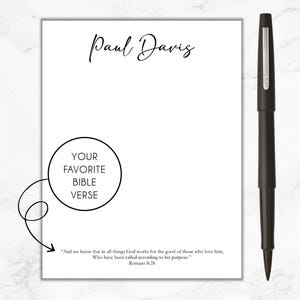 May include: A white notepad with a black pen and the text "Paul Davis" at the top. The notepad has a circle with the text "Your Favorite Bible Verse" and a quote from Romans 8:28.