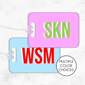 May include: Two luggage tags with white letters on a colored background. The top tag is pink with the letters "SKIN" in green. The bottom tag is light blue with the letters "WSM" in red. The text "MULTIPLE COLOR CHOICES" is below the tags.