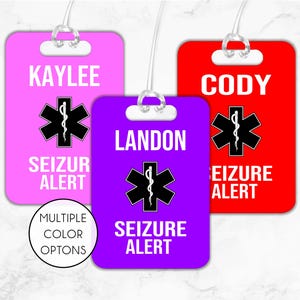 May include: Three luggage tags with the text "Seizure Alert" in white letters on a purple, pink, and red background. Each tag has a white star of life symbol with a snake wrapped around it. The names "Landon", "Kaylee", and "Cody" are printed on each tag.