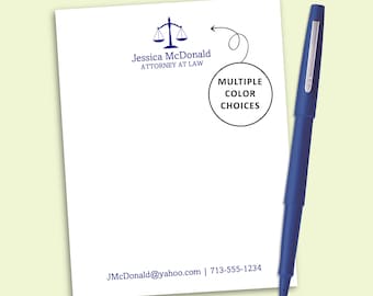 May include: A white notepad featuring a blue scale of justice icon, the text Jessica McDonald ATTORNEY AT LAW, and contact information. A blue pen with a silver clip rests beside it. A circle with an arrow points to the text MULTIPLE COLOR CHOICES.