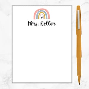 K&ouml;nnte beinhalten: Ein wei&szlig;er Notizblock mit einem Regenbogen-Design und dem Text "Mrs. Keller" oben. Der Regenbogen ist rosa, gelb, blau und grau mit schwarzen Punkten.