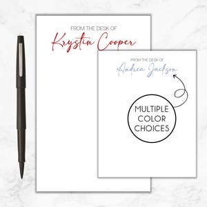 May include: Two white notepads with black text. The top notepad has the text "FROM THE DESK OF Krystin Cooper". The bottom notepad has the text "FROM THE DESK OF Andrea Jackson" and a circle with the text "MULTIPLE COLOR CHOICES".