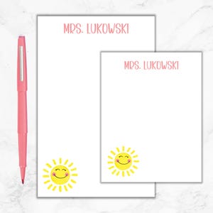 May include: Two white notepads with a pink sun design. The top notepad has the text "MRS. LUKOWSKI" at the top. The bottom notepad has the text "MRS. LUKOWSKI" at the top.