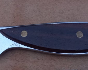 May include: A silver fish-shaped bottle opener with a dark brown wooden handle. The opener has two small brass accents on the handle.