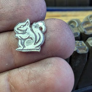 Op de afbeelding: Een witte keramische mok met een zwart handvat en de tekst "But First, Coffee" in een zwarte, handgeschreven lettertype. De mok staat op een wit oppervlak.