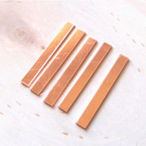 May include: Five rectangular pieces of copper sheet metal, arranged in a row from largest to smallest. The copper has a warm, reddish-brown color.