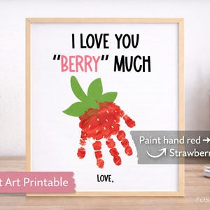 Könnte beinhalten: Gerahmter Druck mit dem Text "I LOVE YOU 'BERRY' MUCH" in Schwarz und Rosa. Ein Handabdruck-Erdbeere befindet sich in der Mitte. Der Text "Handprint Art Printable" steht unten. Das Bild ist in einem Holzrahmen.