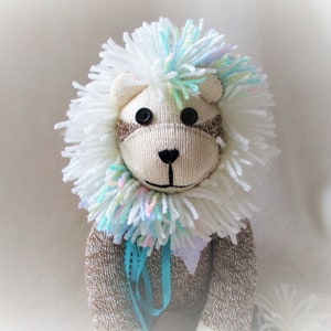May include: A handmade stuffed lion toy with a white and blue yarn mane, brown sock body, and black button eyes.