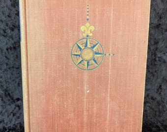 May include: A red book with a compass and fleur-de-lis design on the cover.