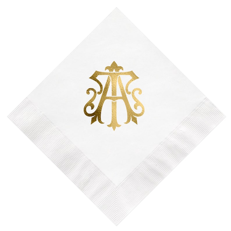 Pu&ograve; includere: Tovagliolo di lino bianco con un monogramma in foglia d'oro delle lettere "A" e "T" in un carattere decorativo.