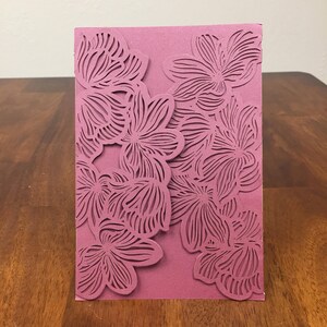 May include: A mauve card with a floral design cut out. The design is intricate and features a variety of flower shapes.