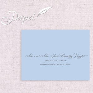 May include: A light blue envelope with a white feather and the text "Papel" in a cursive font. The address is written in cursive: "Mr and Mrs. Jack Bradley Vaught, 2865 E 13TH STREET, GEORGETOWN, TEXAS 78626."