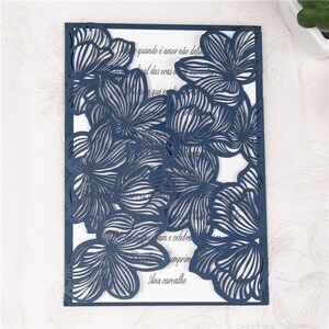 May include: A navy blue laser cut wedding invitation with a floral design. The text on the invitation reads "quando &eacute; amor n&atilde;o def al das eras que ex am e celebre umprim Ana carvalho".