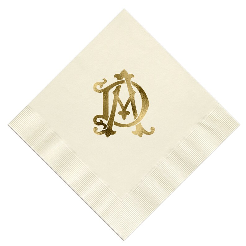 Pu&ograve; includere: Un tovagliolo di lino bianco con un monogramma dorato delle lettere "AM" in un carattere decorativo.