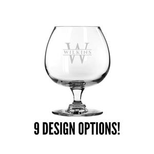 May include: A clear glass brandy snifter with a stem and a wide base. The glass is engraved with the letter "W" and the word "WILKINS" above it.