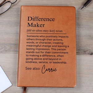 May include: A brown leather journal with the words "Difference Maker" and a definition of the word. The journal also includes the text "See also: Carrie".