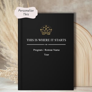 May include: A black journal with gold lotus flower design and the text "THIS IS WHERE IT STARTS". The journal includes space for a program or retreat name and the year. A light pink banner reads "Personalize This".