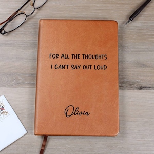 Puede incluir: Un diario de cuero marrón con el texto "For all the thoughts I can't say out loud" y el nombre "Olivia" grabado en la portada.