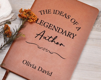 May include: A brown leather journal with the text "THE IDEAS OF A LEGENDARY Author" in black. The name "Olivia David" is printed at the bottom. A decorative floral arrangement rests on the top left corner of the journal.