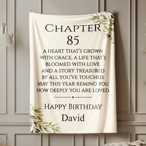 May include: Cream-colored blanket with the text "CHAPTER 85" and a birthday message. The blanket has a floral design in the corners and includes the name "David".