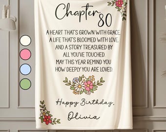 May include: A cream-colored blanket with the text "Chapter 80" and a floral design. The blanket includes the phrases "A heart that's grown with grace" and "Happy Birthday, Olivia."