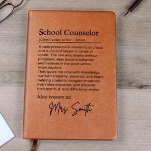 May include: A brown leather journal with the words "School Counselor" and a definition of the role. The text also includes the name "Mrs. Smith".