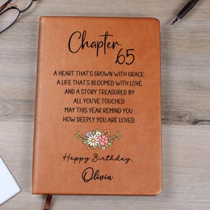 May include: A brown leather-bound journal with the text "Chapter 65" and a floral design. The journal includes the message "Happy Birthday, Olivia" and a heartfelt poem. A perfect gift for a milestone birthday.