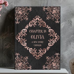 Peut inclure: Un livre personnalisé avec une couverture noire et un motif de filigrane or rose. La couverture présente le texte "Chapter 18 Olivia A New Story Unfolds" dans une police décorative. Le livre a des coins et des bordures ornés.