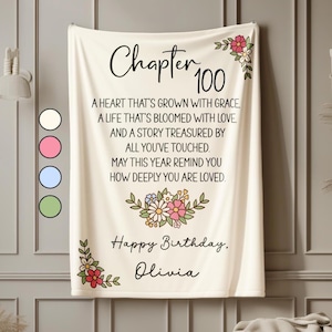 May include: Cream-colored blanket with the text "Chapter 100" and a birthday message. Floral accents in pink, red, and white decorate the corners and center. The message includes the name "Olivia".