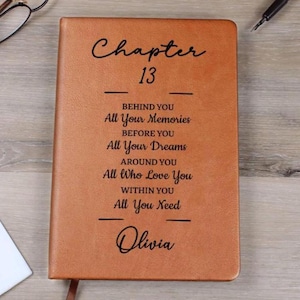 May include: A brown leather-bound journal with the text "Chapter 13" and inspirational phrases. The journal includes the name "Olivia" at the bottom. The cover is a solid, warm brown color.