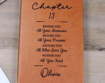 Puede incluir: Un diario de cuero marrón con el texto "Chapter 13" y frases inspiradoras. El diario incluye el nombre "Olivia" en la parte inferior. La cubierta es de color marrón cálido.