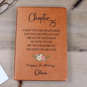 May include: A brown leather-bound journal with the text "Chapter 75" and a floral design. The journal includes a personalized birthday message: "Happy Birthday, Olivia."