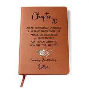 May include: A brown leather-bound journal with the text "Chapter 70" and a floral design. The journal includes the text "Happy Birthday, Olivia" and a poem. A brown ribbon bookmark is attached.