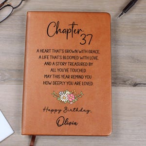 May include: A brown leather journal with the words "Chapter 37" in elegant script. The cover includes a floral design and the text "Happy Birthday, Olivia," along with a heartfelt message. A perfect gift for a birthday.