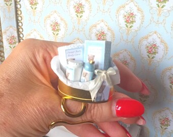 Prezent w postaci zestawu do pielęgnacji ciała dla niemowląt w domku dla lalek. Miniatura wanienki dla niemowląt Just Born w skali 1:12 do domków dla lalek. Miniatura perfum w domku dla lalek.