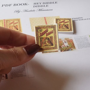 May include: A miniature book titled "Hey Diddle Diddle" with a yellow cover and a cat illustration. The book is part of a set of miniature books for dollhouses.