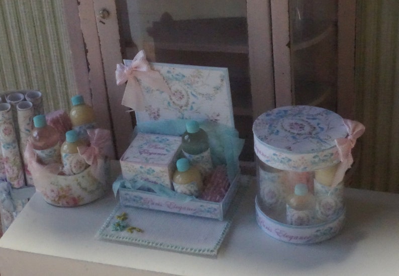 May include: A set of decorative gift boxes with a floral design. The boxes are filled with small bottles of liquid and are decorated with ribbons and bows. The boxes are on a white surface.