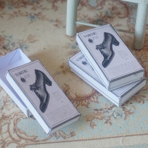 May include: Three white shoe boxes with black and white illustrations of shoes. The boxes are labeled "Norvic" and have a vintage aesthetic.