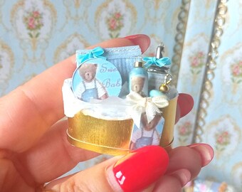 Prezent w postaci zestawu do pielęgnacji ciała dla niemowląt w domku dla lalek. Miniatura wanienki dla niemowląt Just Born w skali 1:12 do domków dla lalek. Miniatura perfum w domku dla lalek.