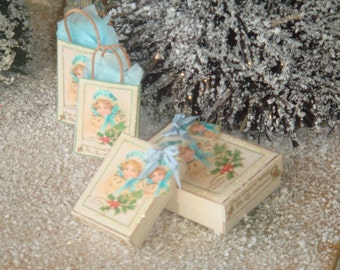 May include: Four small gift boxes with blue ribbon and a vintage Christmas design featuring children. The boxes are on a white surface with a snowy texture.
