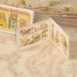 May include: A vintage children's book titled "Funny Zoological ABC". The book is open to pages featuring illustrations of animals and letters of the alphabet.