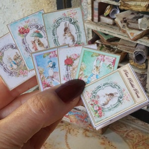 Op de afbeelding: Een set van zes vintage-stijl kaarten met illustraties van konijnen en vogels. De kaarten zijn gedrukt op een lichtblauwe achtergrond met roze en witte bloemenaccenten. De kaarten zijn ongeveer 7,6 cm bij 7,6 cm groot. De kaarten zijn gelabeld "Rose Petite Prints".