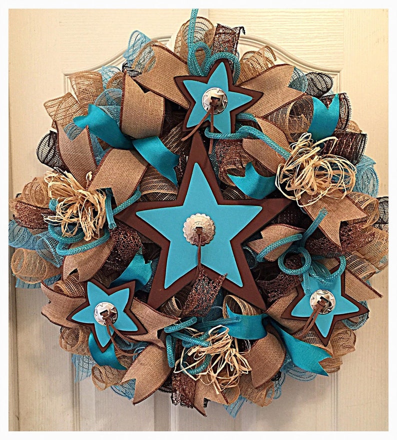 May include: A turquoise and brown star-shaped wreath with burlap and brown ribbon accents. The wreath features three large stars with brown outlines and silver accents.