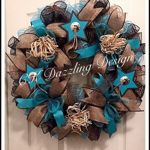 May include: A turquoise and brown burlap wreath with star-shaped embellishments and a brown ribbon. The wreath has a rustic, western theme.