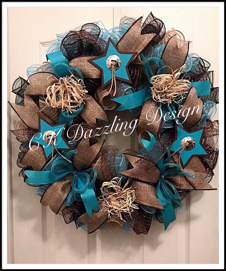 May include: A turquoise and brown burlap wreath with star-shaped embellishments and a brown ribbon. The wreath has a rustic, western theme.