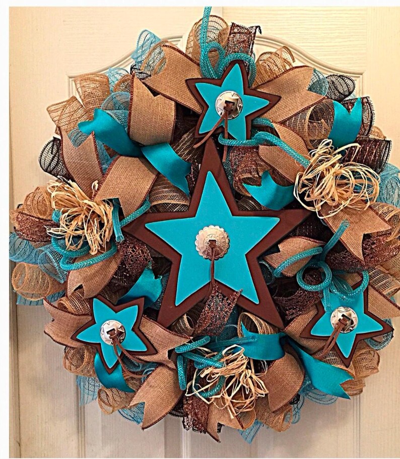 May include: A turquoise and brown star-shaped wreath with burlap and brown ribbon accents. The stars have a brown outline and a silver concho in the center.