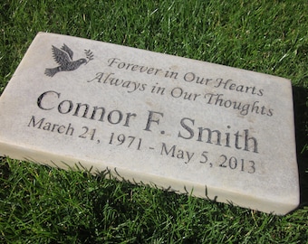 May include: A light gray rectangular memorial stone with the inscription "Forever in Our Hearts Always in Our Thoughts Connor F. Smith March 21, 1971 - May 5, 2013". A dove with an olive branch is engraved in the top left corner.
