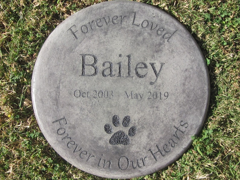 以下が含まれることがあります： 「Forever Loved Bailey Oct 2003 - May 2019 Forever in Our Hearts」と肉球の跡が刻まれた灰色のコンクリート製の記念石です。
